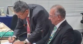 Presidente do TRE-RJ (à esq.) assina o termo de posse como 1º vice-presidente do Coptrel ao lado...