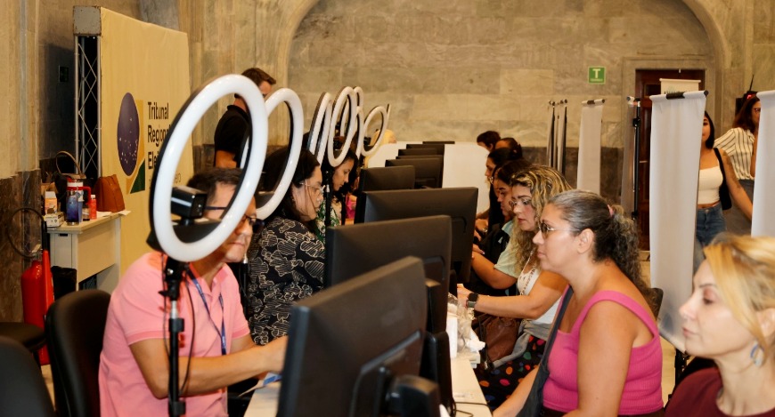 Guichês de atendimento no Grande Hall do Palácio da Democracia; sete pessoas estão sentadas, sen...