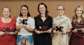 A imagem mostra cinco mulheres em pé, lado a lado, segurando troféus com as letras "ME" destacad...