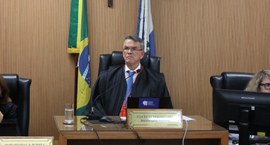 Foto do presidente do TRE-RJ, desembargador Claudio de Mello Tavares, sentado à mesa, sobre o qu...