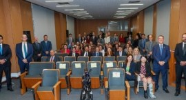 Grupo de aproximadamente 50 juízas e juízes no auditório do Palácio da Democracia. Estão vestido...