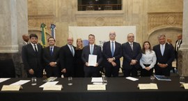 Imagem de autoridades, atrás de uma mesa, após a assinatura de um pacto interinstitucional contr...