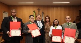 a foto mostra seis pessoas posando juntas no Plenário do TRE-RJ, que tem paredes amadeiradas. No...