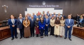 Grupo de autoridades posando juntas dentro de um plenário. Eles estão posicionados à frente do b...