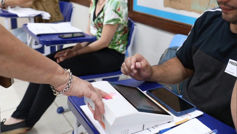 Uma servidora da Justiça Eleitoral colhe a biometria de um eleitor.