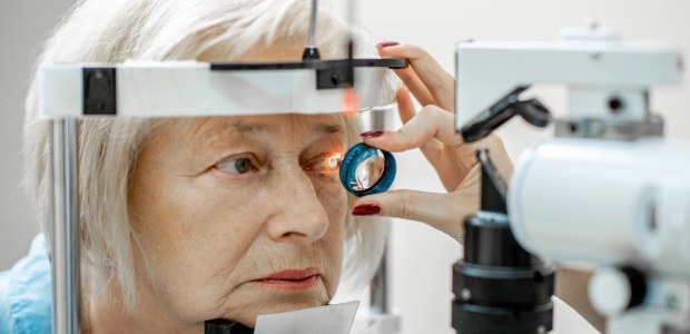 Descrição da imagem: Mulher idosa realizando exame oftalmológico em clínica, com equipamento de ...