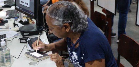 A aposentada Rosana Freitas faz a assinatura digital durante a coleta de seus dados biométricos