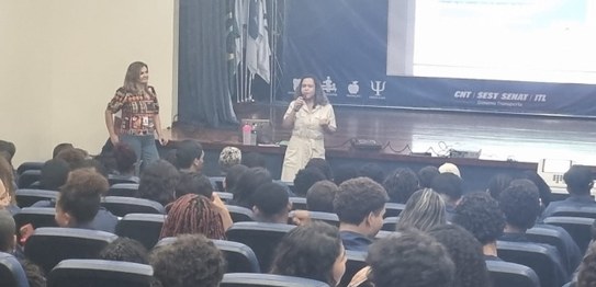 Turma de estudantes sentados em cadeiras verdes, assistindo a uma palestra conduzida por juíza. ...