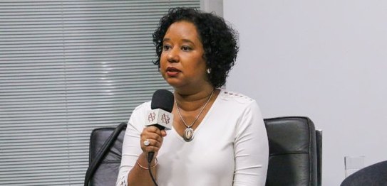 Três pessoas estão sentadas em um semicírculo; da esquerda para a direita, Ana Flávia Magalhães ...