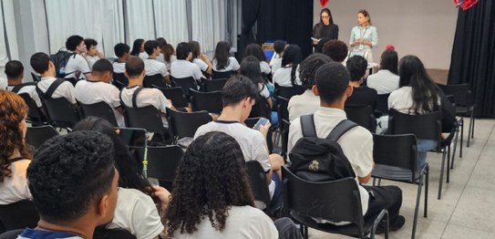 Duas mulheres estão em pé conduzindo uma palestra para um grupo de estudantes em uma sala de aula.
