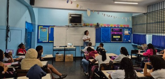 Servidora da Justiça Eleitoral realiza palestra sobre cidadania para estudantes, que estão senta...