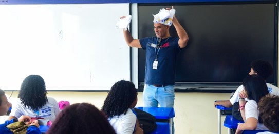 Duas mulheres estão em pé conduzindo uma palestra para um grupo de estudantes em uma sala de aula.