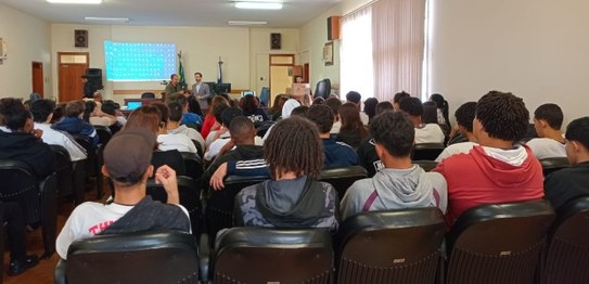 Servidora da Justiça Eleitoral realiza palestra sobre cidadania para estudantes, que estão senta...