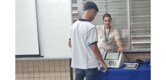 O juiz Luiz Olímpio Mangabeira Cardoso ajuda um estudante de Sapucaia a utilizar a urna eletrônica