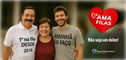 Três pessoas sorriem lado a lado em um ambiente externo. À esquerda, um homem de bigode usa uma ...