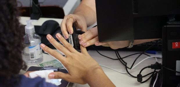 Com foco nas mulheres, TRE-RJ participará de ação de atendimento a pessoas em situação de vulnerabilidade Duas mulheres interagem durante o atendimento do TRE-RJ. Uma delas está segurando o aparelho par...