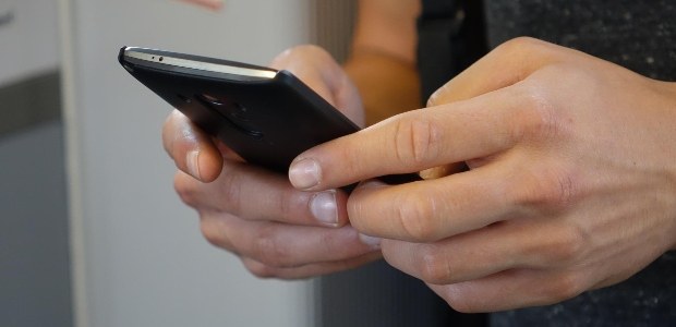 Close das mãos de uma pessoa segurando um celular