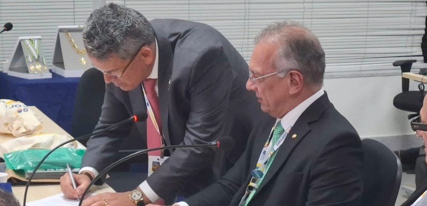 Presidente do TRE-RJ (à esq.) assina o termo de posse como 1º vice-presidente do Coptrel, ao lad...