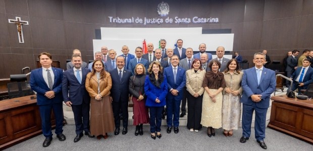 Grupo de autoridades posando juntas dentro de um plenário. Eles estão posicionados à frente do b...
