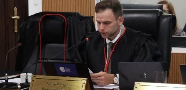 Desembargador eleitoral Bruno Bodart sentado, olhando para baixo, realizando um discurso.