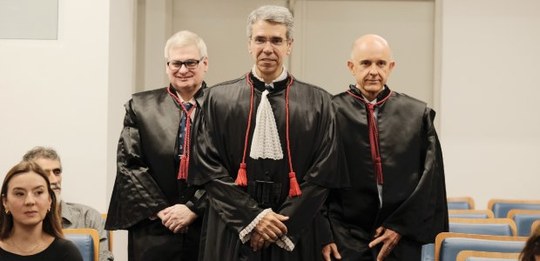 Três desembargadores estão usando toga, entrando no plenário do TRE-RJ. Ao centro o empossado, d...