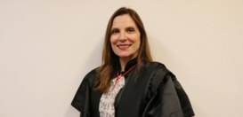 Foto posada da desembargadora Maria Helena Pinto Machado, sorrindo, de cabelos lisos compridos e...