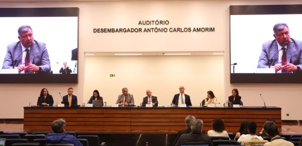 Desinformação nas eleições é tema de palestra promovida pela Emerj_ Mesa de autoridades em um auditório, com oito pessoas sentadas participando de um evento ou pale...