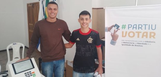 Dois alunos do Colégio Estadual Coronel João Limongi posam ao lado da urna eletrônica, eles atua...