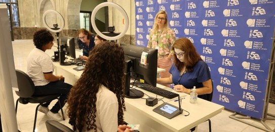 Um grupo de pessoas de diversas idades posa no plenário do TRE-RJ.