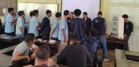 A imagem mostra uma sala de aula com alunos vestidos com uniformes escolares azuis, participando...