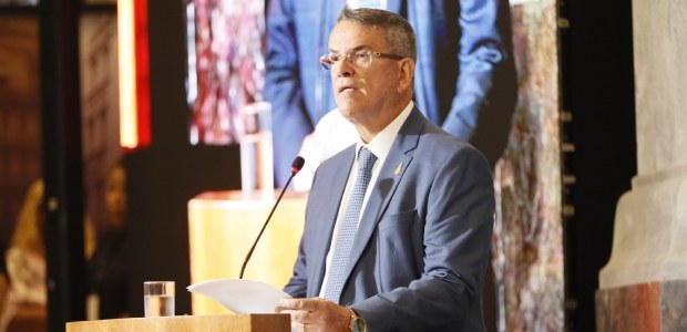 O presodente do TRE-RJ, Claudio de Mello Tavares, em pé em um pódio de madeira. Ele está olhando...