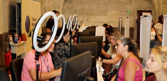 Guichês de atendimento no Grande Hall do Palácio da Democracia; sete pessoas estão sentadas, sen...