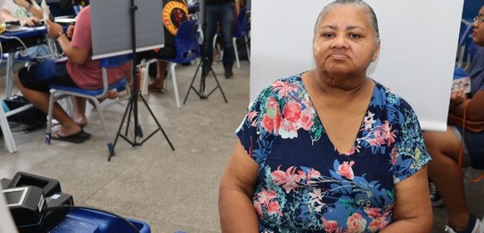 Duas eleitoras posam para foto, tendo ao fundo pessoas sentadas; às esquerda, mulher negra, com ...
