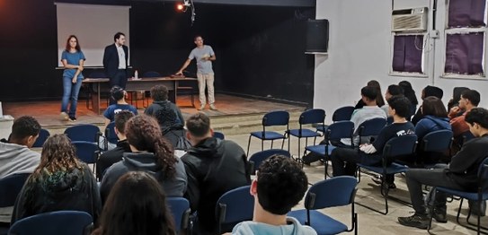 Duas mulheres estão em pé conduzindo uma palestra para um grupo de estudantes em uma sala de aula.