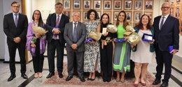 Foto posada dos participantes do evento. São nove pessoas que usam roupas formais e estão numa s...