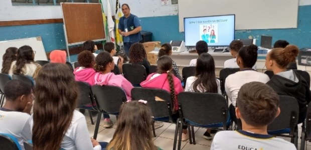 Escolas em Itaguaí e Volta Redonda recebem o programa “Eleitor do Futuro” Descrição da imagem: alunos assistem sentados a palestra do servidor Ary Nogueira, de pé ao fund...