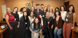 Um grupo de aproximadamente quinze estudantes e profissionais sorri e se junta para uma foto em ...