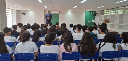 Palestrante realiza apresentação em sala com estudantes e responsáveis, com apoio de materiais i...