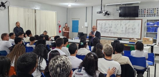 Turma de estudantes sentados em cadeiras verdes, assistindo a uma palestra conduzida por juíza. ...