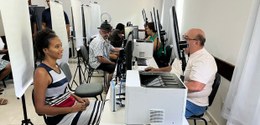 A imagem mostra um ambiente de atendimento ao público, possivelmente um mutirão ou ação social p...