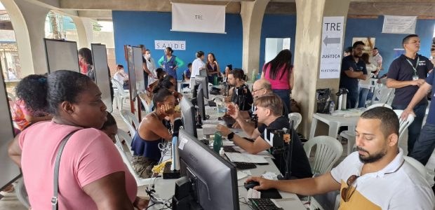 Justiça Itinerante do TRE-RJ faz atendimento em Macaé Foto colorida dos guichês de atendimento do TRE-RJ na ação social. Separados por uma mesa, a ima...