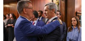 O presidente do TRE-RJ, de terno azul, está de perfil, sorrindo e cumprimentando o ministro Marc...