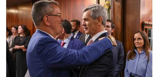 O presidente do TRE-RJ, de terno azul, está de perfil, sorrindo e cumprimentando o ministro Marc...