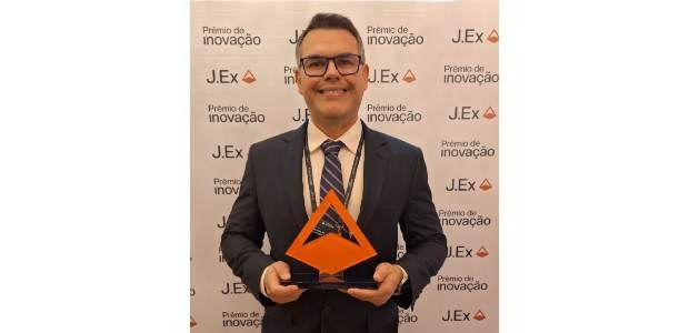 Michel Kovacs posa com troféu, em formato piramidal, ao lado de dez integrantes da equipe da TI,...