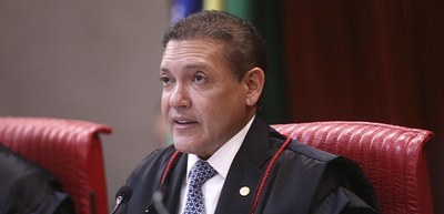 Ministro Nunes Marques usa toga; ao fundo, bandeira do Brasil
