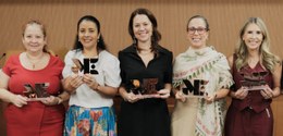 A imagem mostra cinco mulheres em pé, lado a lado, segurando troféus com as letras "ME" destacad...