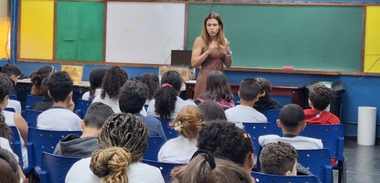 Duas mulheres estão em pé conduzindo uma palestra para um grupo de estudantes em uma sala de aula.
