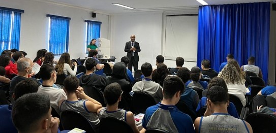 Numa sala, sentadas(os), estudantes assistem à palestra do juiz eleitoral Livingstone dos Santos...