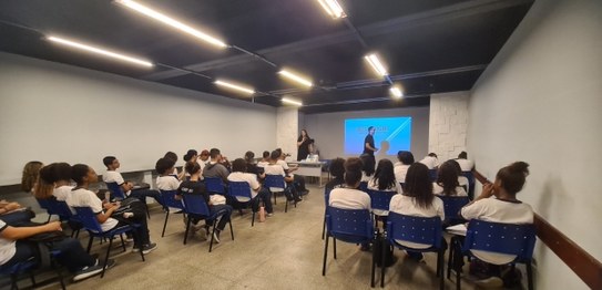 Numa sala, sentadas(os), estudantes assistem à palestra do juiz eleitoral Livingstone dos Santos...