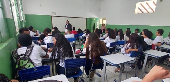 Numa sala, sentadas(os), estudantes assistem à palestra do juiz eleitoral Livingstone dos Santos...